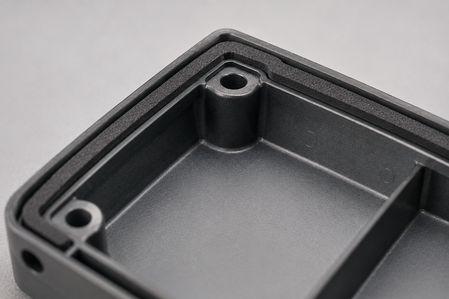 Custom silicone foam gasket positioned on an electronic enclosure sealing surface